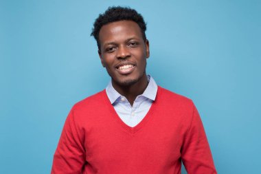 Yakışıklı Afrikalı adam mavi duvarda gülümsüyor.