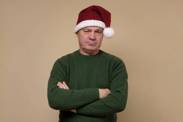 Triste homme âgé en chapeau de Père Noël l'air en colère. — Photo