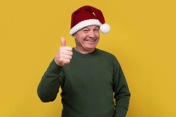 Senior homme portant santa claus chapeau faire des pouces heureux geste avec la main — Photo