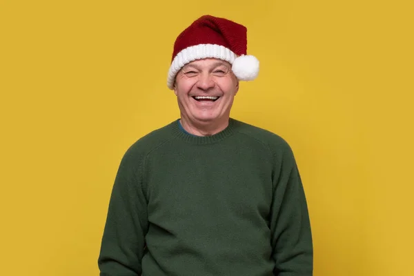 Heureux homme âgé célébrant Noël, portant le chapeau de Père Noël riant à haute voix — Photo