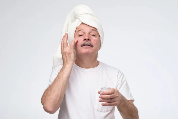 Зрелый мужчина использует крем для кожи лица — стоковое фото