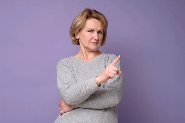 Mujer mayor con expresión de rechazo haciendo signo negativo diciendo no. — Foto de Stock