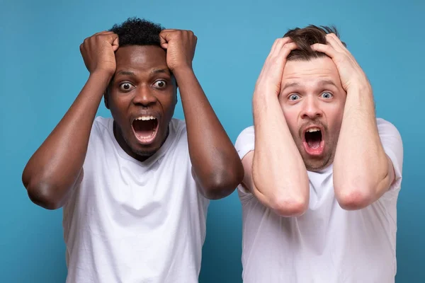 Afrikaanse en blanke mannen zijn bang en geschokt door onverwacht nieuws.. — Stockfoto