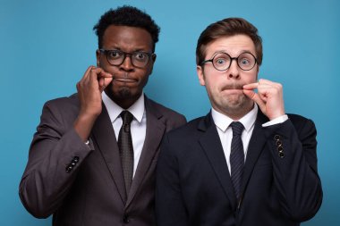 İki Afrikalı ve beyaz adam çenelerini parmaklarıyla kapatıyor.