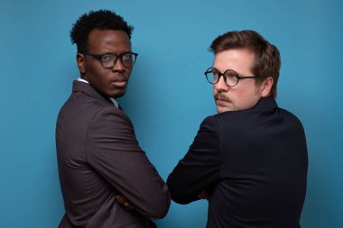 İki Afrikalı ve beyaz takım elbiseli adam kızgın bir şekilde geri dönüyorlar.