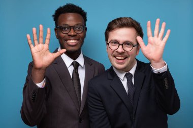 İki beyaz ve Afrikalı adam selamlaşıp el sallıyor..