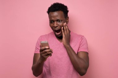 Genç Afrikalı bir adam şaşkınlıkla akıllı telefondan mesaj alır..