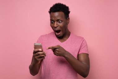 Genç Afrikalı bir adam şaşkınlıkla akıllı telefondan mesaj alır..