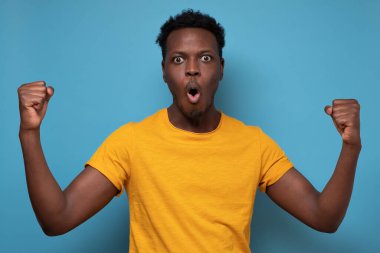 Mutlu heyecanlı Afrikalı adam çığlık atıyor ve başarıyı iki yumrukla kutluyor.