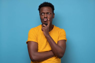Afrikalı adam şüpheyle bakıyor, tereddütleri var, ne yapacağını düşünüyor.