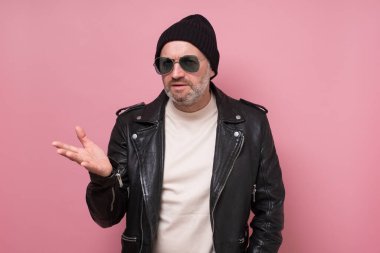 Sakallı hoşnutsuz adam aktif olarak el kol hareketi yapıyor, tartışırken kaşlarını çatıyor.