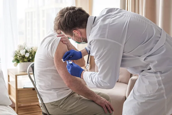 Médico vacunando a un paciente masculino mayor en casa. —  Fotos de Stock