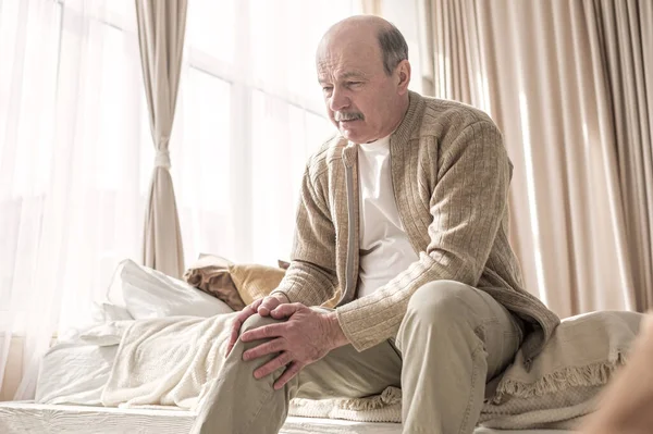Senior man med artros smärta hålla händerna på knät — Stockfoto