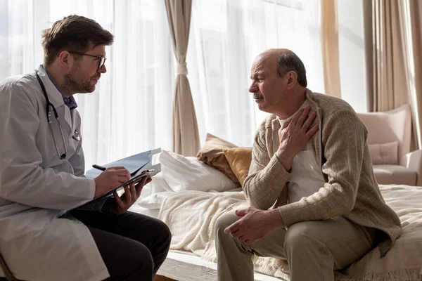 Доктор слухає скарги літнього чоловіка, які відвідують його вдома — стокове фото