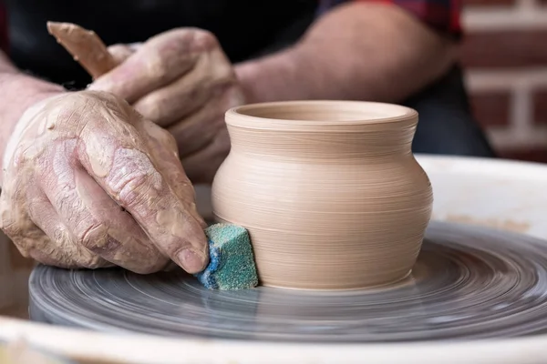 Mãos masculinas limpeza com cerâmica esponja em uma roda de oleiro. — Fotografia de Stock