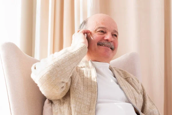 Senior man in gesprek op mobiele telefoon met zijn familie in de woonkamer. — Stockfoto