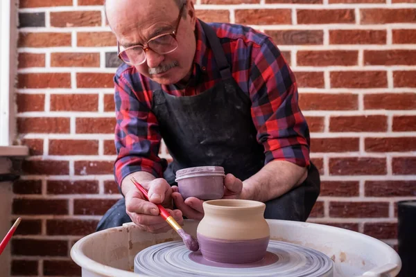 老年人拿着刷子，用陶瓷轮在陶瓷上作画. — 图库照片