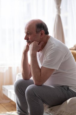 Kafkasyalı üzgün bir adam yatağında oturuyor, kafası elinde.