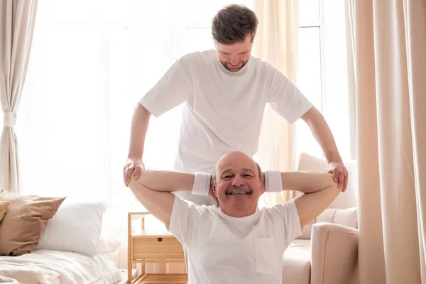 Hombre entrenador de yoga ayuda al hombre mayor a hacer asana correctamente. — Foto de Stock