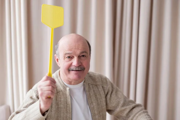 Senior caucasian man holding a fly swatter wanting to kill annoying mosquito — Stock Photo, Image