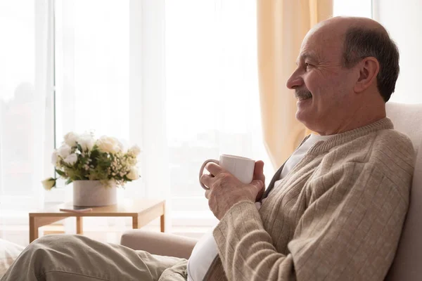 Vreugdevolle senior met een witte koffiekop dromend over toekomstplannen — Stockfoto