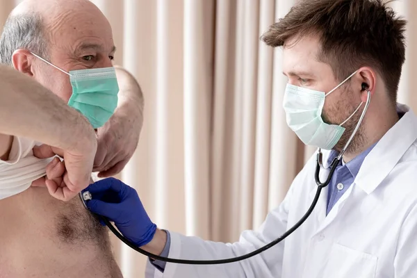 Лікар - самець Кавказу слухає, як старші чоловіки дихають стетоскопом. — стокове фото