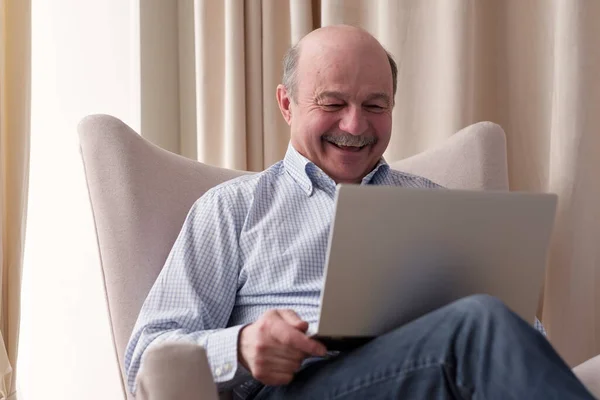 Homem sênior conectado na internet com laptop em casa — Fotografia de Stock