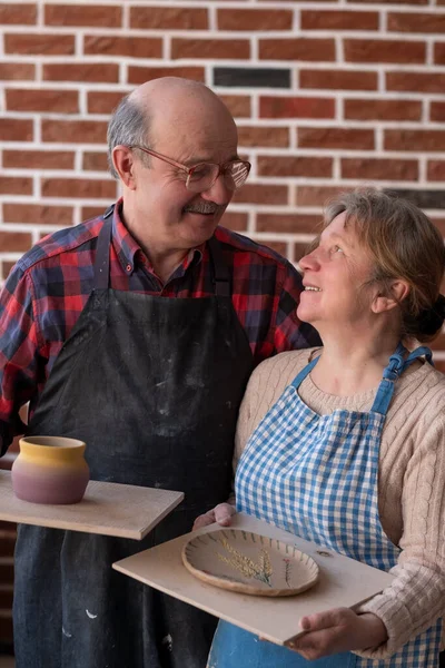 Senior paar man en vrouw met handgemaakte pot en bord na workshop — Stockfoto