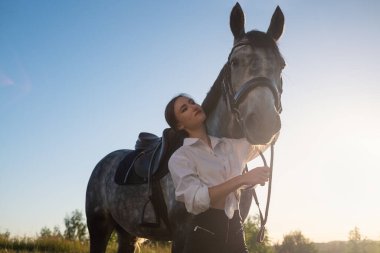 Genç ve güzel bir kadın atına bakıyor, sarılıyor..