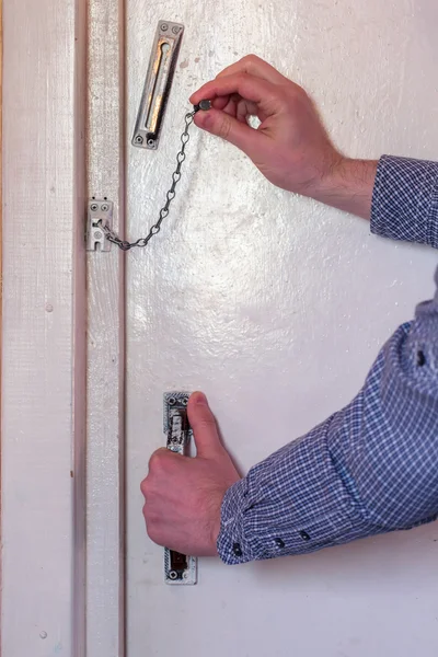 The man opens the door, opens chain — Stock Photo, Image
