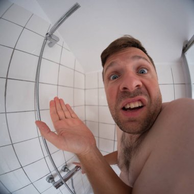 Duşun altında susuz duran bir adam, evdeki su kesintisinden etkilenmiş. Yüksek kalite fotoğraf