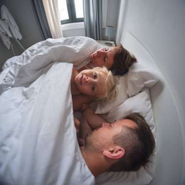 4 yaşındaki küçük bir kız sabah ailesini uyandırıyor ve uyumalarına izin vermiyor. Yüksek kalite fotoğraf