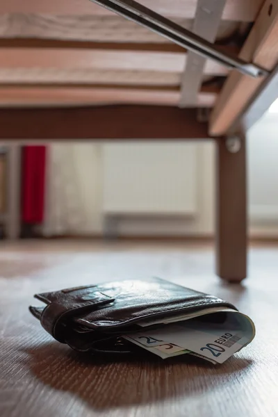 Bolso con el dinero caído por casualidad debajo de la cama . — Foto de Stock