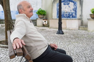 Yaşlı bir İspanyol adam bir bankta otururken dinleniyor, dışarıda sakin bir anın tadını çıkarıyor ve hayatın geçişini seyrediyor. Yüksek kalite fotoğraf