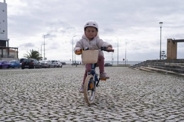 İki tekerlekli bisiklete binen kask takan küçük bir kız. Yüksek kalite fotoğraf