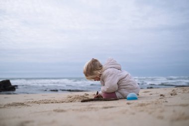 Soğuk sonbahar havasında sahilde oynayan küçük bir kız. Yüksek kalite fotoğraf