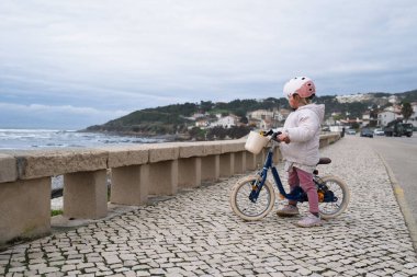 İki tekerlekli bisiklete binen kask takan küçük bir kız. Yüksek kalite fotoğraf