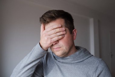 Stresli adam gözlerini sıkıca kapatıyor, tatsız bir gerçekle yüzleşmeyi reddediyor. Yüksek kalite fotoğraf