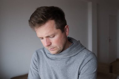 Üzgün ve hayal kırıklığına uğramış genç bir adam umutsuzluk duygusuyla aşağıya bakıyor. Yüksek kalite fotoğraf