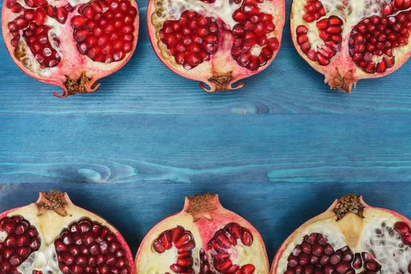 Cut in half pomegranate on a wooden blue surface — Stockfoto