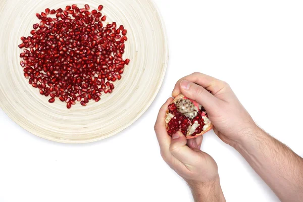 Piatto pieno di semi di melograno pelati e un uomo de-semina frutta — Foto Stock