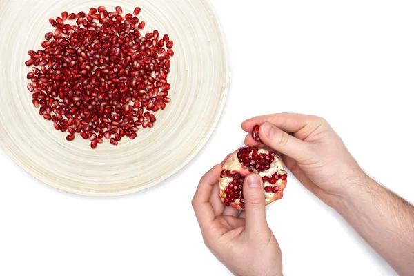 Piatto pieno di semi di melograno pelati e un uomo de-semina frutta — Foto Stock