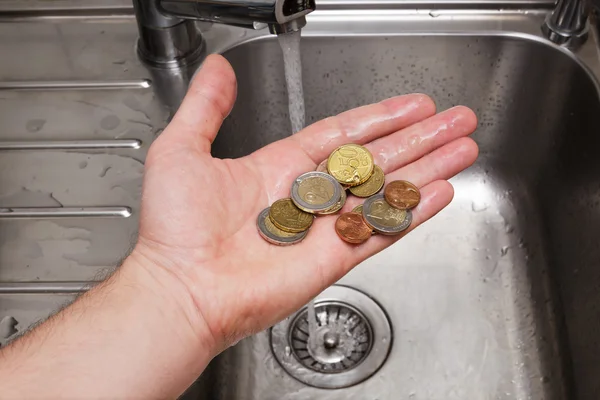 Hombre lavando monedas bajo el agua corriente — Foto de Stock