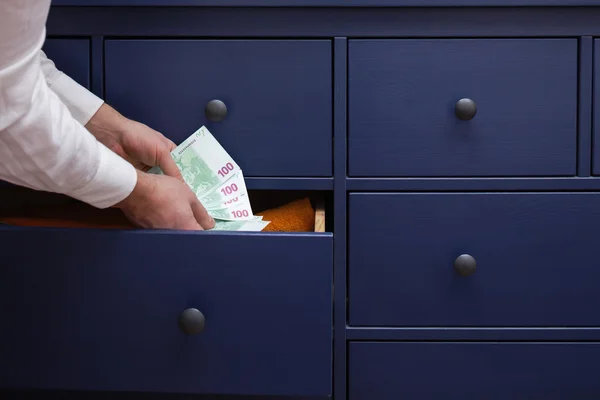 Man hides a salary in euros in a drawer — Stock Photo, Image