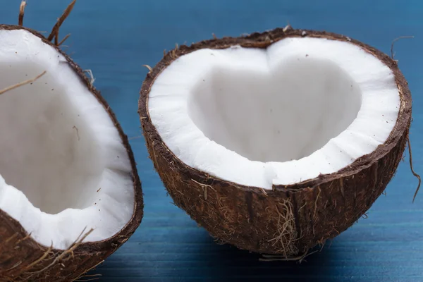 Coco picado: metades de coco na forma de um coração em um blu — Fotografia de Stock
