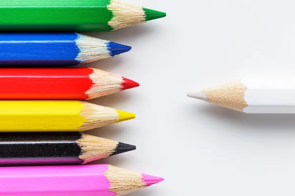 Один белый карандаш и цветные карандаши — стоковое фото