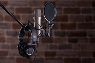 Stüdyo yoğunlaştırıcı mikrofon. Kulaklıkları taş desenli arka planda.