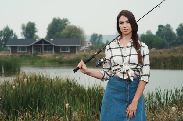 Kraju kobieta stojąca przed staw na ranczo z ryb pręt — Zdjęcie stockowe