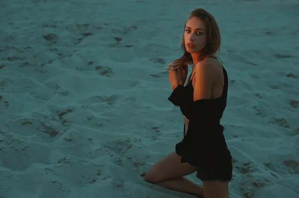 Sexig blond haired ung kvinna poserar i sanden i öknen upplyst av röda inställningen solen ljus — Stockfoto