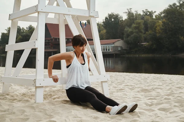 Barna, rövid hajvágás csinál, stretching river beach — Stock Fotó